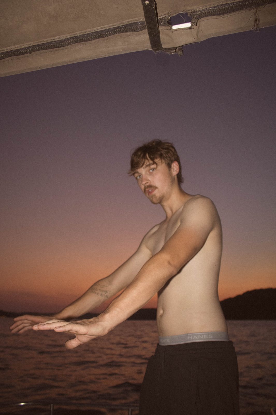 04Riley reaching toward the sunset over the water