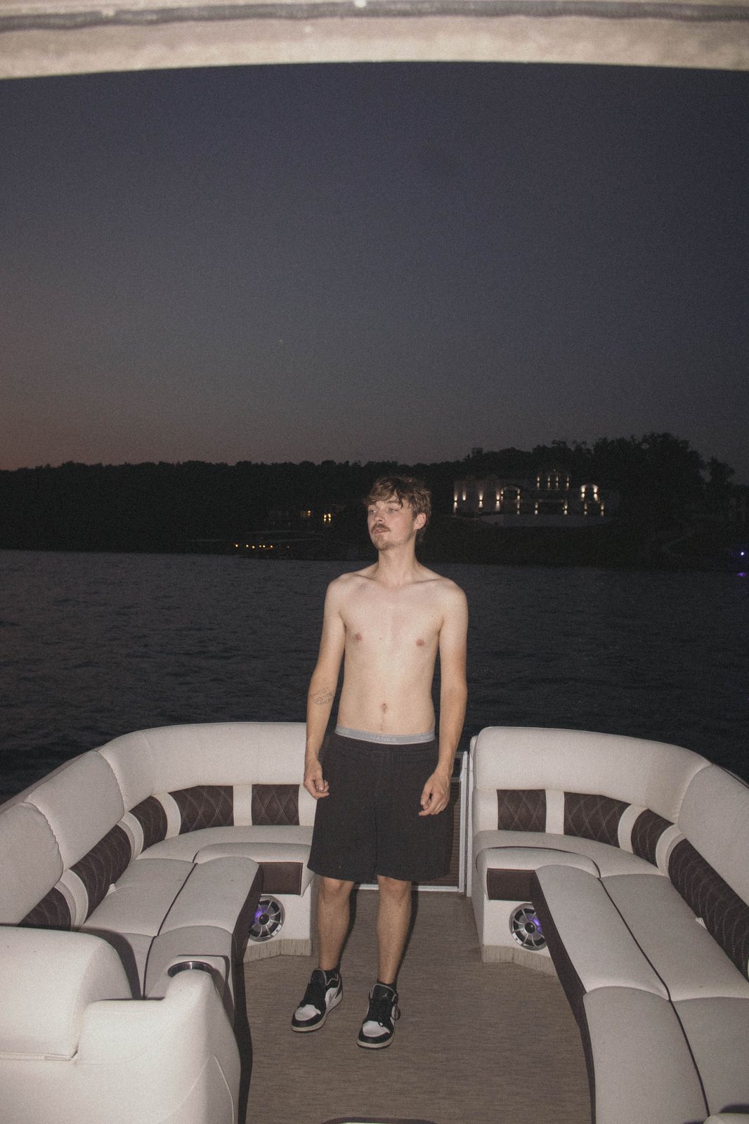 04Riley on the pontoon with a lake house lit behind him