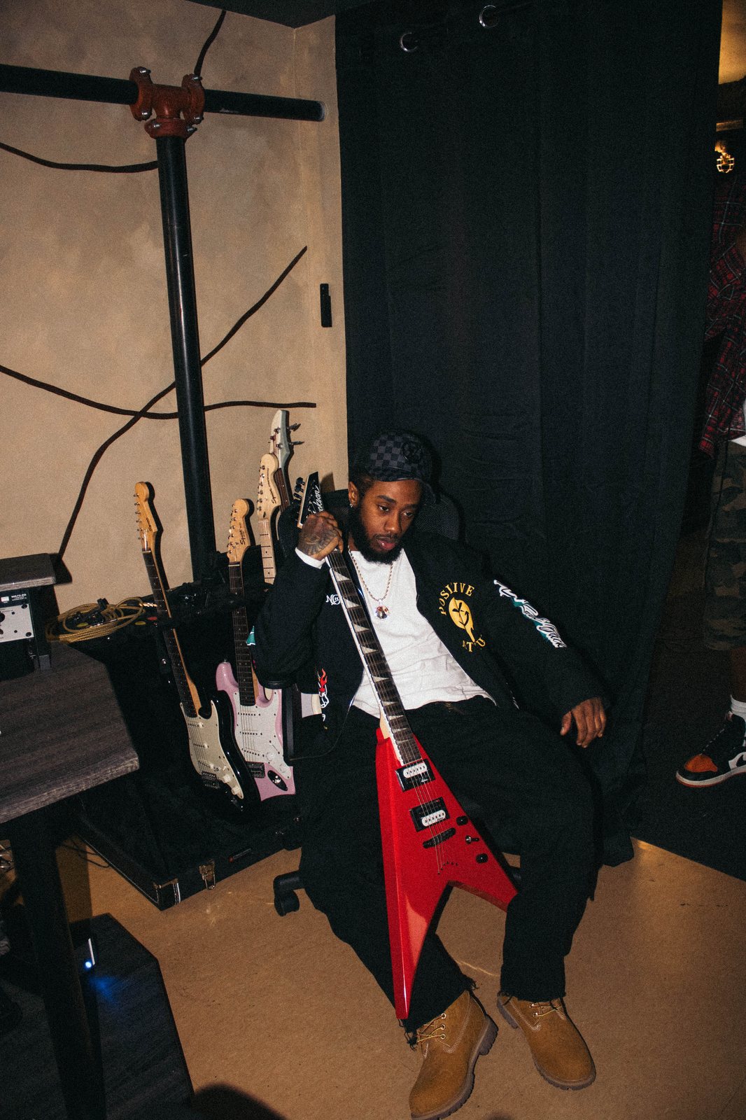 STBtheDON seated in the studio holding a red Flying V guitar